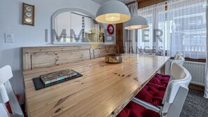 A modern dining area with a wooden table, white chairs, and pendant lights.
