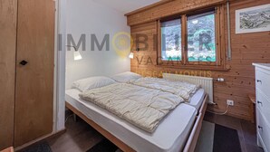 A bedroom with a bed, a window, a radiator, and wooden walls.