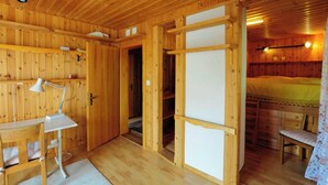 Ein Holzblockhaus mit Schreibtisch, Stuhl und einem Bett.