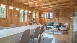 A wooden cabin interior with a dining table, chairs, a sofa, and a fireplace. - Chalet en bois de mélèze, typique et authentique avec énormément de charme. Idéal pour les familles, (St-Luc)