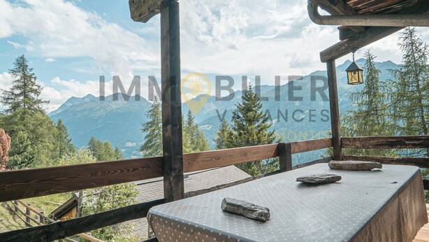 A wooden deck with a table and benches, overlooking a mountainous landscape. - Chalet en bois de mélèze, typique et authentique avec énormément de charme. Idéal pour les familles, (St-Luc)