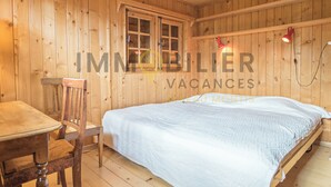 A wooden room with a bed, a chair, and a table. - Chalet en bois de mélèze, typique et authentique avec énormément de charme. Idéal pour les familles, (St-Luc)