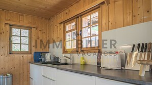 A wooden-paneled kitchen with a sink, a toaster, and a knife block. - Chalet en bois de mélèze, typique et authentique avec énormément de charme. Idéal pour les familles, (St-Luc)