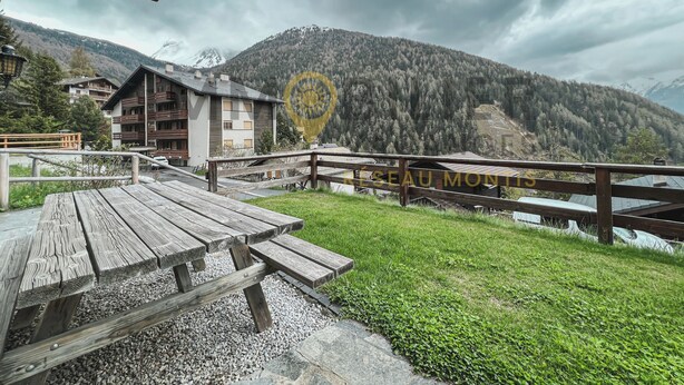 A wooden deck with a picnic table, a wooden fence, and a mountain backdrop. - Idéalement situé, à proximité du vieux village, à 2' à pied du départ du funiculaire. Chalet sur 2 n (St-Luc)
