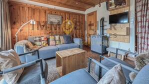 A cozy living room with wooden paneling, a blue sofa, a wooden coffee table, and a fireplace. - Idéalement situé, à proximité du vieux village, à 2' à pied du départ du funiculaire. Chalet sur 2 n (St-Luc)