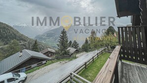 A mountain view with a wooden deck and a road leading to houses. - Idéalement situé, à proximité du vieux village, à 2' à pied du départ du funiculaire. Chalet sur 2 n (St-Luc)