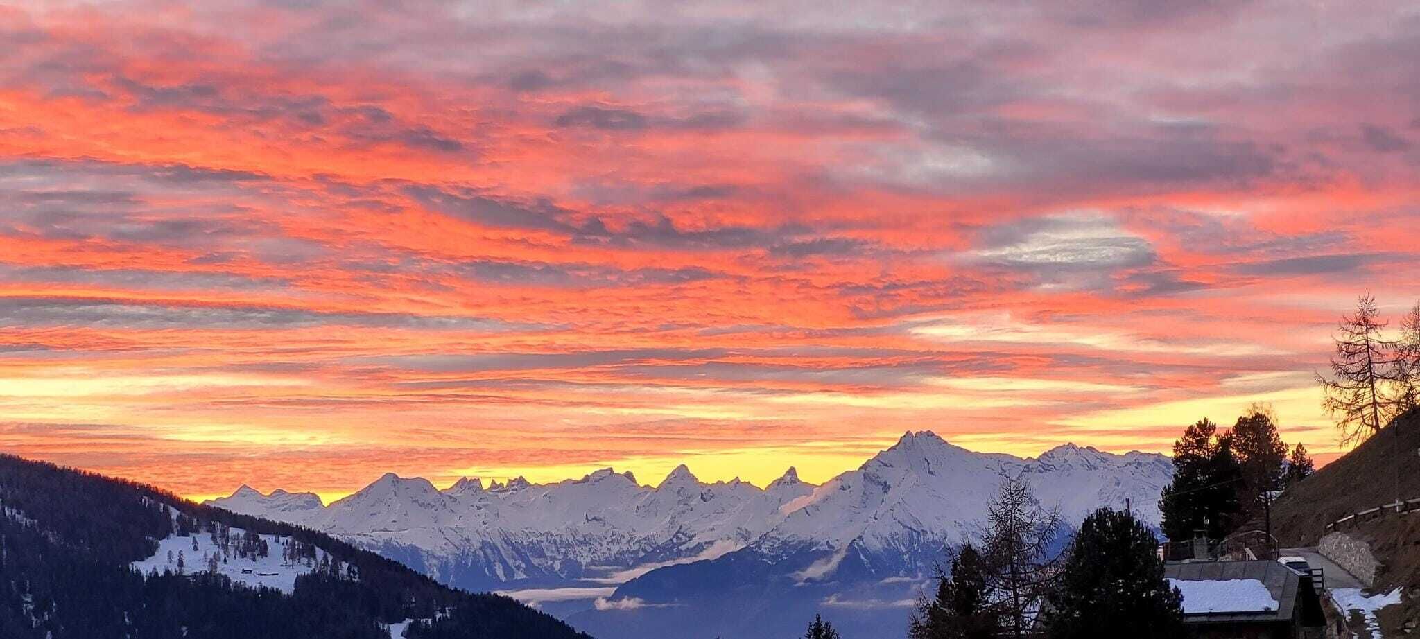 Un paisaje montañoso con picos nevados y un cielo al atardecer.