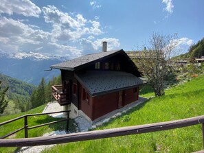 Experience serene mountain views from the wooden balcony of this chalet-style lodge, nestled in a lush valley.