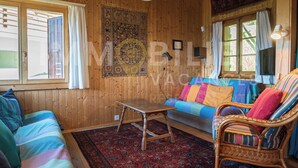A cozy room with wooden walls, a colorful sofa, a wicker chair, and a small table. - Ce charmant chalet est parfait pour accueillir une famille de 4 personnes. Vous trouverez deux chamb (Chandolin)