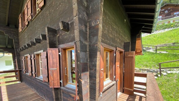 A wooden cabin with multiple windows, a wooden deck, and a staircase leading to an upper level. - Ce charmant chalet est parfait pour accueillir une famille de 4 personnes. Vous trouverez deux chamb (Chandolin)