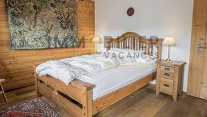 Un lit en bois avec un matelas blanc, une table de chevet avec une lampe et une grande tapisserie au mur.