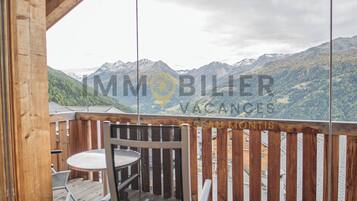 Eine Holzterrasse mit Tisch und Stühlen mit Blick auf eine Berglandschaft.