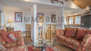 A spacious living room with patterned sofas, a glass coffee table, and a wooden staircase. - Très beau chalet récent de tout confort situé directement au vieux village, avec un accès aisé. Idéa (St-Luc)