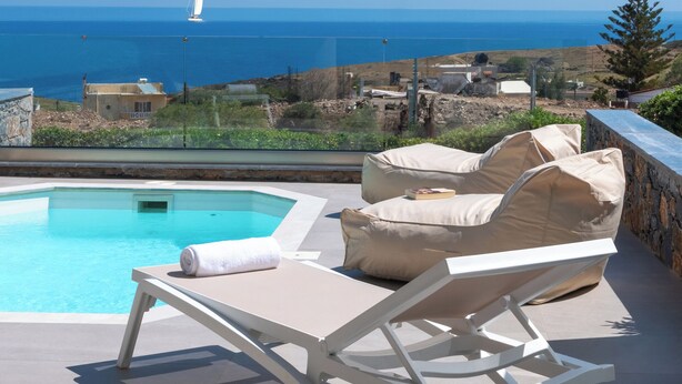 Zona de piscina amb gandules i vista al mar.