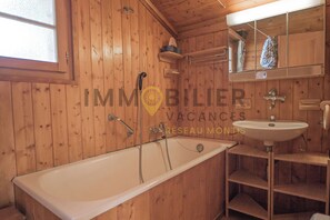 A wooden cabin bathroom with a bathtub, a sink, and a mirror. - Charmant chalet individuel situé dans le bas du village de St-Luc, idéal pour 4 à 6 personnes. Avec (St-Luc)