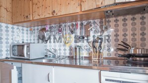 Una cocina con armarios de madera, microondas, lavabo y diversos utensilios.