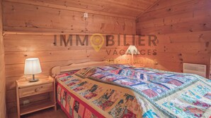 Una habitación de cabaña de madera con una cama, una mesita de noche y una lámpara.