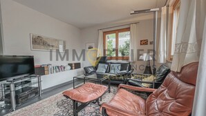 Een woonkamer met een bank, een voetenbankje en een flatscreen-televisie.