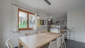 Een moderne keuken met witte kasten, een houten aanrecht en een hangende lamp.