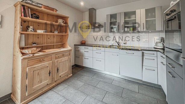 Een moderne keuken met houten kastjes, een inbouwoven en een koffiezetapparaat.