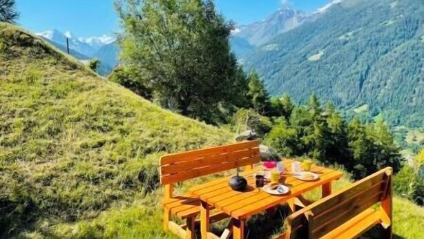A wooden table and benches set on a grassy hillside with a mountain view. - Charming detached two-storey chalet for 7 (to 8) people. Splendid view of the Imperial Crown with th (St-Luc)