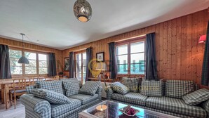 A cozy cabin-style room with a checkered sofa set, a glass coffee table, and wooden walls. - Charming detached two-storey chalet for 7 (to 8) people. Splendid view of the Imperial Crown with th (St-Luc)