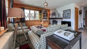 A cozy living room with plaid furniture, a fireplace, and a bookshelf. - Charming detached two-storey chalet for 7 (to 8) people. Splendid view of the Imperial Crown with th (St-Luc)