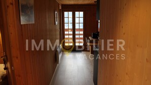 Un pasillo de madera que conduce a una habitación con un ventanal y una puerta.