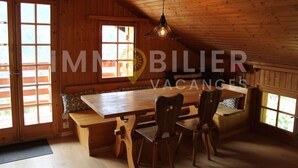 A wooden interior with a large table and chairs, a bench, and a hanging light fixture. - From the two parking spaces, a series of approximately twenty steps will lead you to this charming a (St-Luc)