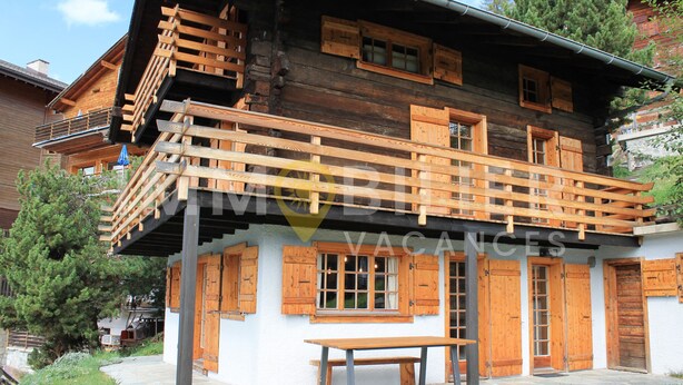 A wooden chalet with a balcony, a stone bench, and a wooden table. - From the two parking spaces, a series of approximately twenty steps will lead you to this charming a (St-Luc)