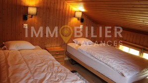 A cozy cabin-style room with two single beds, wooden walls, and a sloped ceiling. - From the two parking spaces, a series of approximately twenty steps will lead you to this charming a (St-Luc)