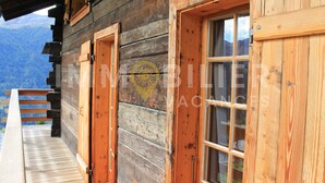 Una cabaña de madera con balcón, puertas y ventanas de madera.