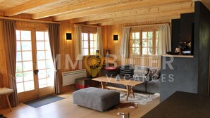 Un interior de madera acogedor con sofá, reposapiés y una mesa de comedor.