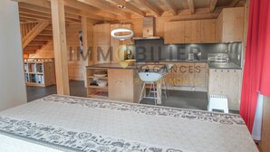 A modern kitchen with wooden cabinetry, a central island, and a hanging light fixture. - Magnifique chalet confortable, moderne, de 195m2, 5 pièces  avec 4 chambres et pouvant accueillir ju (St-Luc)