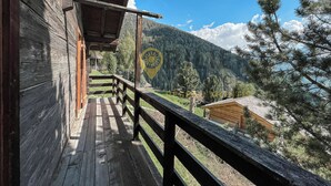 A wooden cabin with a balcony overlooking a mountainous landscape.