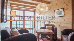 A cozy room with wooden walls, a round table, and leather sofas. - Très beau chalet contemporain avec une vue splendide !Très lumineux, construction sur 3 niveaux, sit (St-Luc)