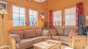 A cozy cabin with a checkered sofa, a wooden table, and a television. - Très beau chalet chaleureux et confortable, meublé et décoré avec beaucoup de goût. Spacieux et lumi (St-Luc)
