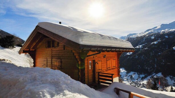 A wooden cabin with a sloped roof, surrounded by snow and mountains. - Très beau chalet chaleureux et confortable, meublé et décoré avec beaucoup de goût. Spacieux et lumi (St-Luc)