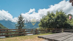 A wooden picnic table with benches, a wooden fence, and a view of mountains and a lake. - Ideally located near the old village and a 2-minute walk from the funicular railway. Two-storey chal (St-Luc)
