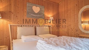 A wooden-paneled room with a bed, pillows, a wall-mounted sign, and a lamp. - Ideally located near the old village and a 2-minute walk from the funicular railway. Two-storey chal (St-Luc)