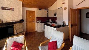 A cozy interior with a wooden ceiling, a fireplace, and a kitchen area. - Idéalement situé, au pied des pistes, en face du funiculaire. Appartement agréable et chaleureux, au (St-Luc)