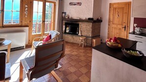 A cozy living room with a fireplace, wooden ceiling, and large windows. - Idéalement situé, au pied des pistes, en face du funiculaire. Appartement agréable et chaleureux, au (St-Luc)