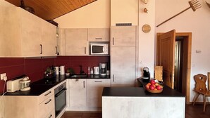 A kitchen with wooden ceiling, a microwave, a coffee maker, and a fruit bowl on the counter. - Idéalement situé, au pied des pistes, en face du funiculaire. Appartement agréable et chaleureux, au (St-Luc)