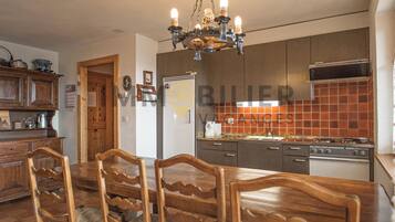 Une cuisine avec des meubles de rangement en bois, une cuisinière et une table à manger avec des chaises.
