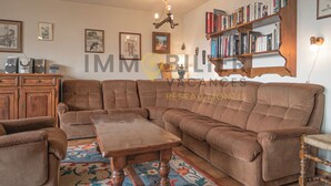 A living room with a sectional sofa, a wooden coffee table, and a bookshelf filled with books. - Au pied des pistes, en face du funiculaire et à 5' à pied du centre du vieux village ! Appartement c (St-Luc)