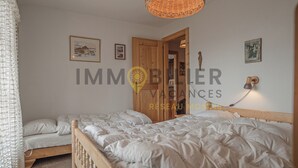 A bedroom with two beds, a wooden wardrobe, and a hanging light fixture. - Au pied des pistes, en face du funiculaire et à 5' à pied du centre du vieux village ! Appartement c (St-Luc)