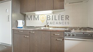 A kitchen with wooden cabinets, a stainless steel stove, and a white tiled backsplash. - Idéalement situé, au pied des pistes, en face du funiculaire et à 5' à pied du centre du vieux villa (St-Luc)