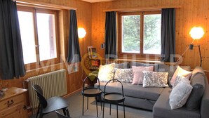 A cozy room with a grey sofa, two black chairs, a wooden dresser, and a radiator. - Charmant 2 pièces pour 2 à 4 personnes au rez d'un chalet. Situé à 300 mètres de l'arrêt du bus nave (Chandolin)