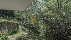 A stone staircase leading up to a building with a covered entrance, surrounded by lush greenery and trees. - Charmant 2 pièces pour 2 à 4 personnes au rez d'un chalet. Situé à 300 mètres de l'arrêt du bus nave (Chandolin)
