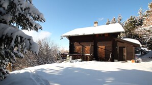 A wooden cabin with a snow-covered roof, surrounded by snow-covered trees and a clear blue sky. - Charmant 2 pièces pour 2 à 4 personnes au rez d'un chalet. Situé à 300 mètres de l'arrêt du bus nave (Chandolin)
